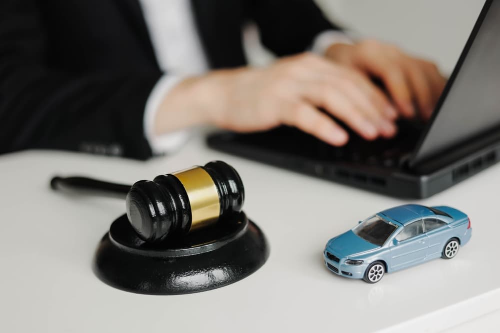 Car Accident lawyer working on laptop beside judge's gavel and car model