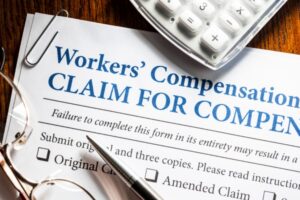 Workers’ compensation document with gavel and money rolls symbolizing legal claims and financial benefits for workplace injuries.