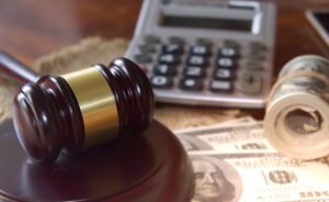 Judge’s gavel with money and calculator symbolizing legal costs and financial settlements