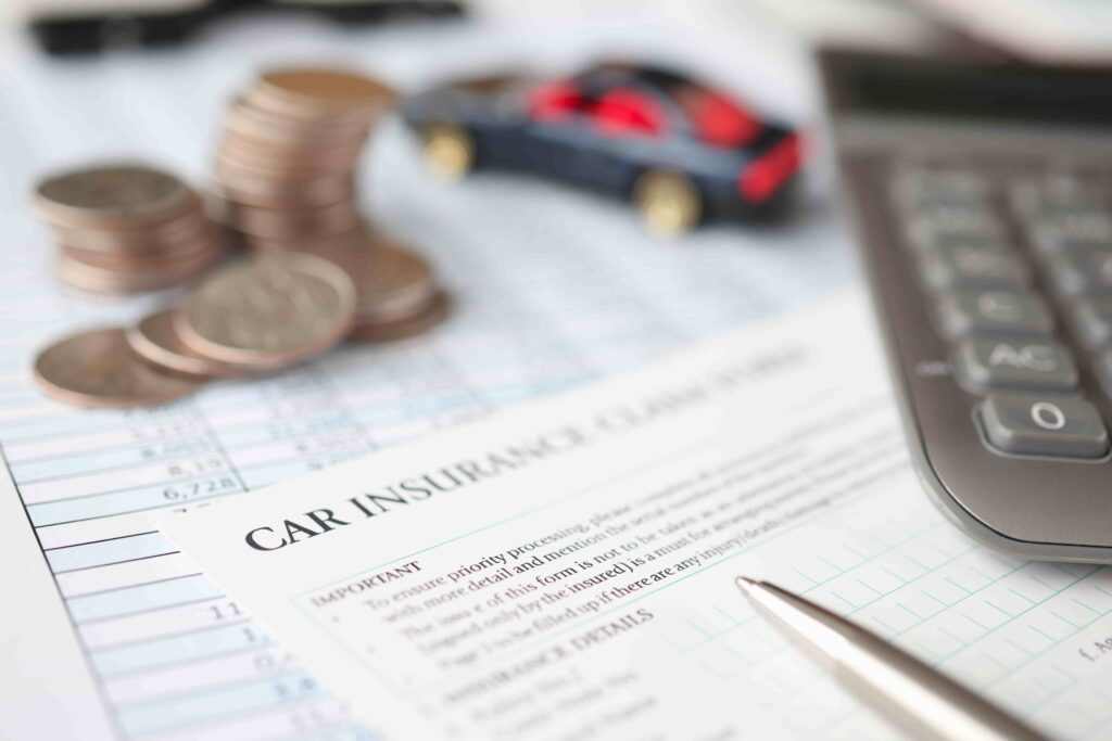 Car insurance claim form with calculator, coins, and toy car symbolizing auto accident compensation