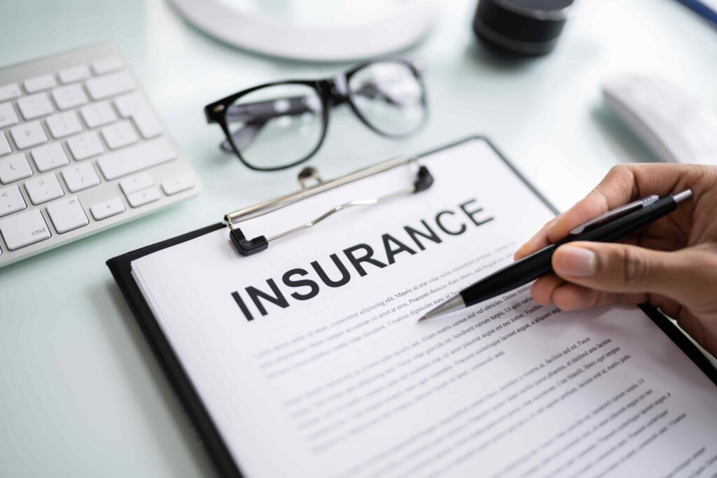 Insurance policy document with pen and glasses on desk for coverage and claims review.