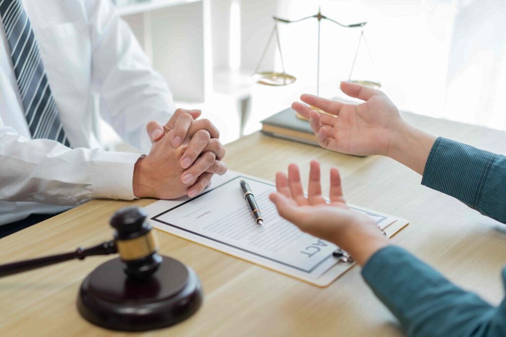 Client consulting with lawyer in office about legal contract with gavel and scales of justice on desk