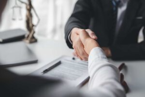 Lawyer and client shaking hands over legal documents in office