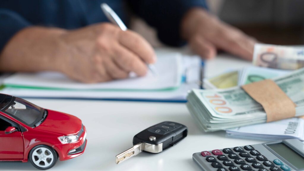 Car accident insurance claim with toy car, car keys, money, and paperwork on desk