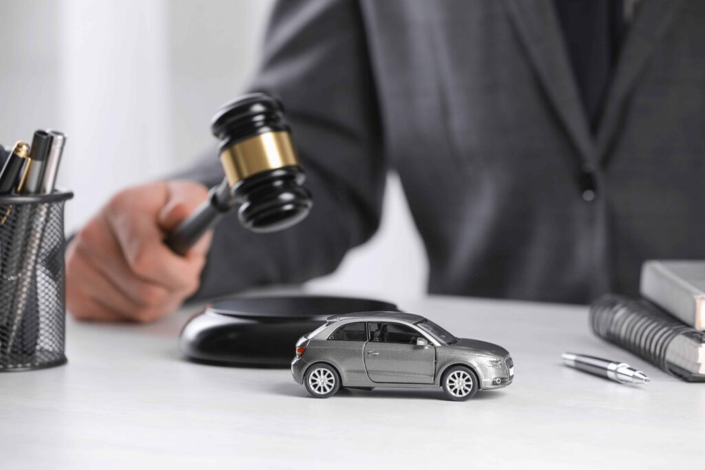Judge with gavel next to toy car symbolizing car accident lawsuit and auto insurance claims
